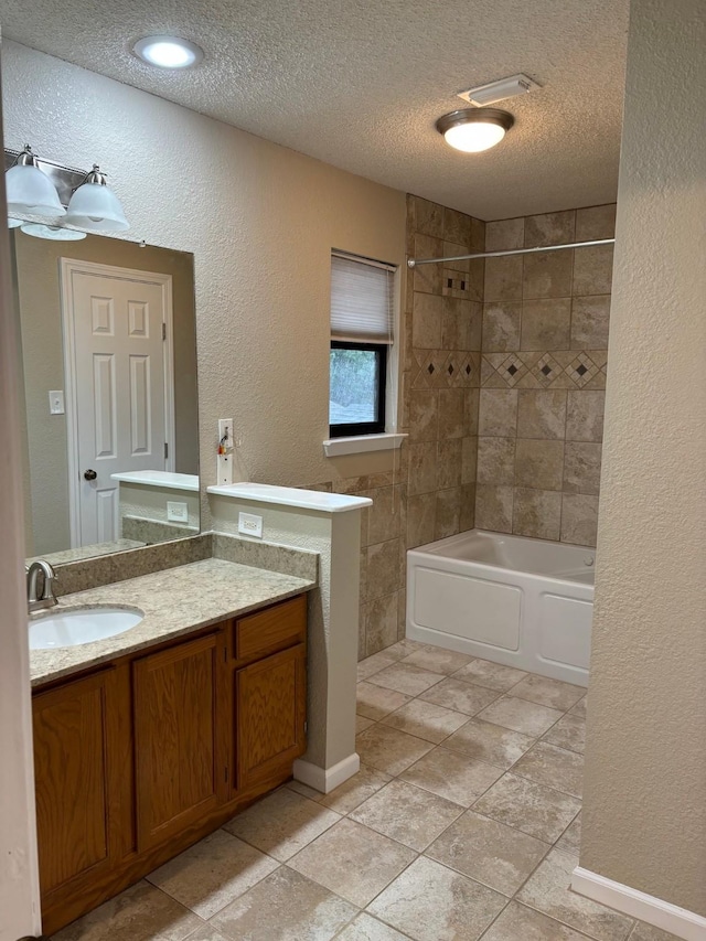 bathroom featuring vanity, a textured ceiling, tiled shower / bath combo, and tile patterned flooring