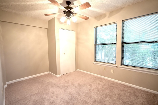 unfurnished bedroom featuring a textured ceiling, light colored carpet, and ceiling fan