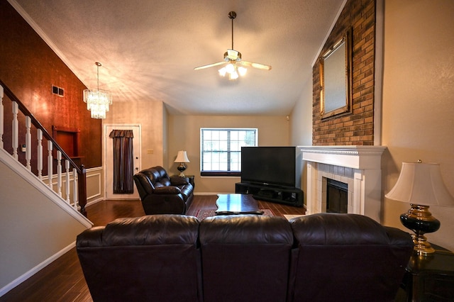 living room featuring dark hardwood / wood-style flooring, ceiling fan with notable chandelier, a textured ceiling, lofted ceiling, and a tiled fireplace