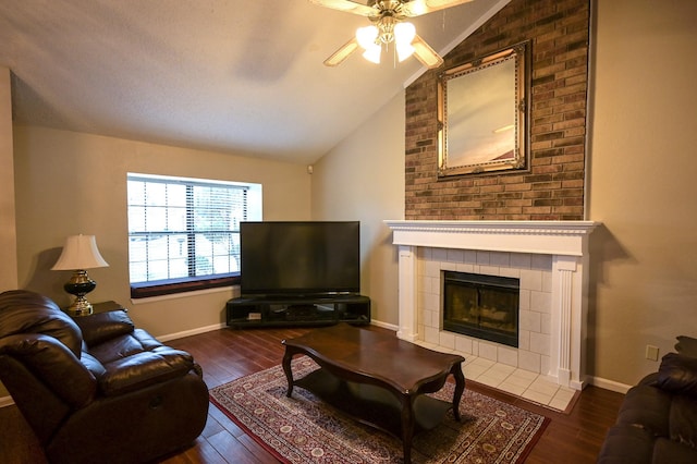 living room with ceiling fan, a fireplace, lofted ceiling, and dark wood-type flooring