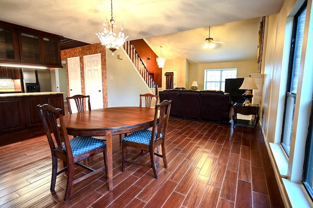 dining room with a textured ceiling, ceiling fan with notable chandelier, and vaulted ceiling