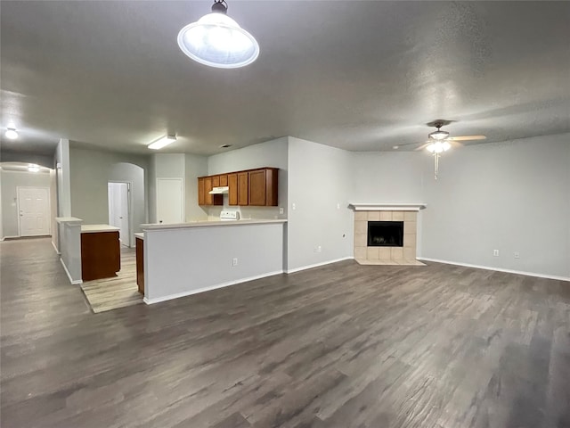 unfurnished living room featuring ceiling fan, dark hardwood / wood-style flooring, and a tile fireplace