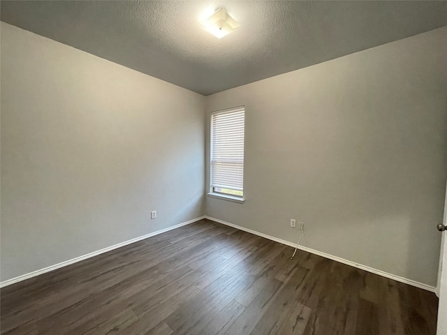 spare room featuring dark wood-type flooring and a textured ceiling