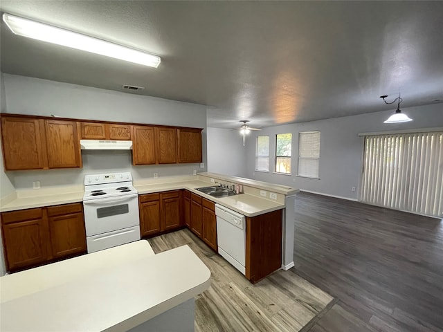 kitchen featuring kitchen peninsula, hardwood / wood-style floors, sink, decorative light fixtures, and white appliances