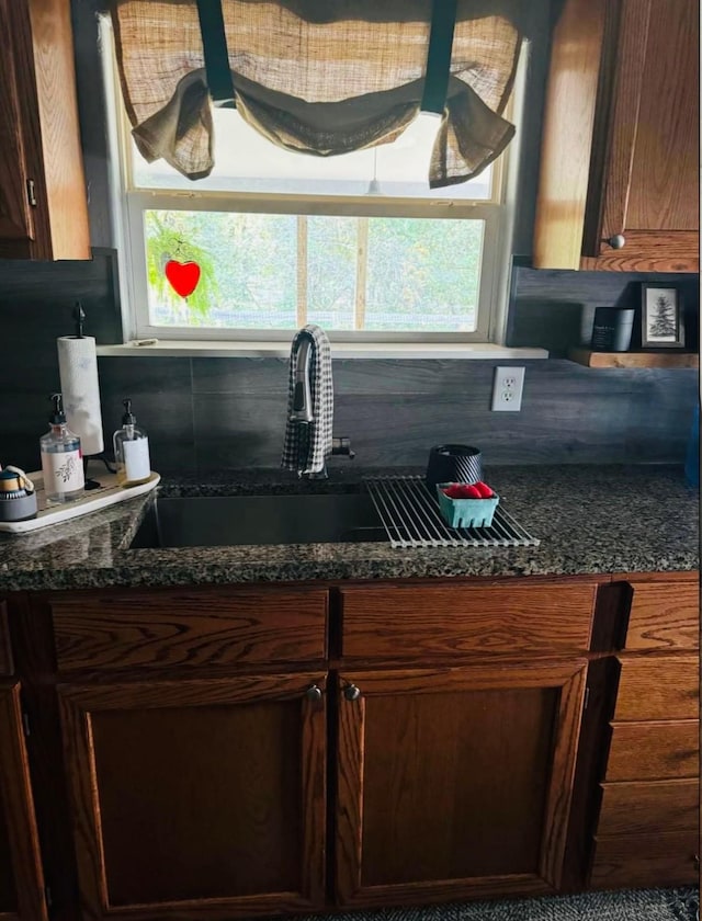 kitchen featuring sink, backsplash, and dark stone countertops