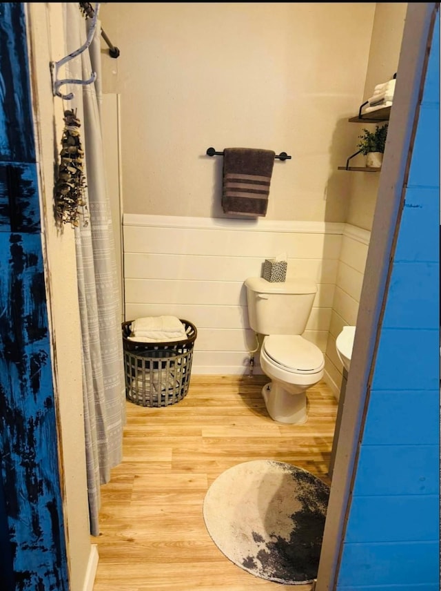 bathroom featuring toilet, a shower with curtain, and hardwood / wood-style floors