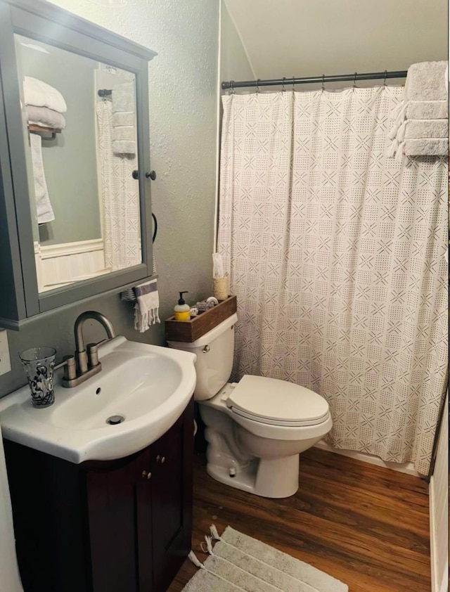 bathroom featuring toilet, a shower with shower curtain, hardwood / wood-style flooring, and vanity