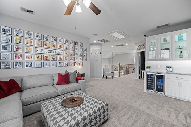 carpeted living room with wine cooler, bar, and ceiling fan