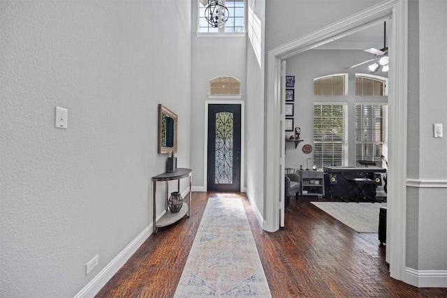 entryway featuring a towering ceiling, plenty of natural light, dark hardwood / wood-style floors, and ceiling fan