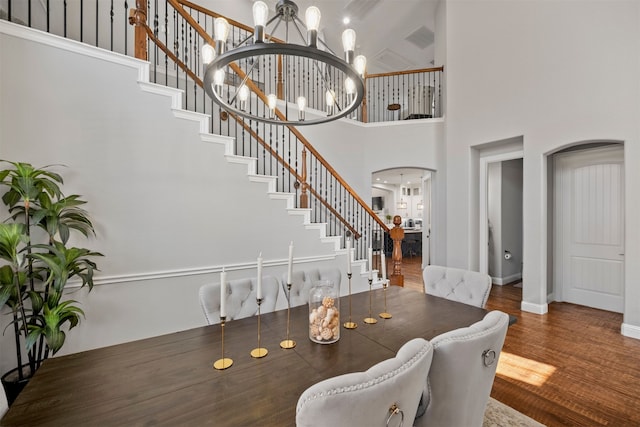 dining room featuring dark wood-type flooring, an inviting chandelier, and a towering ceiling