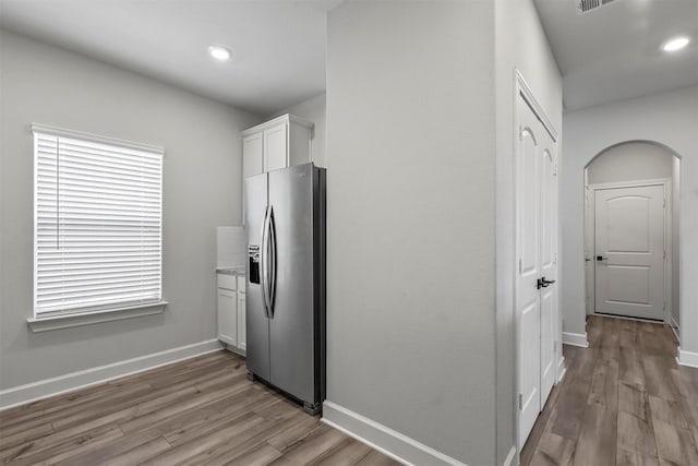 kitchen with light hardwood / wood-style floors, stainless steel fridge, and white cabinetry