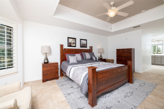 tiled bedroom featuring crown molding, ensuite bathroom, a raised ceiling, and ceiling fan