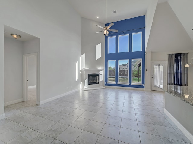 unfurnished living room featuring ceiling fan and a towering ceiling