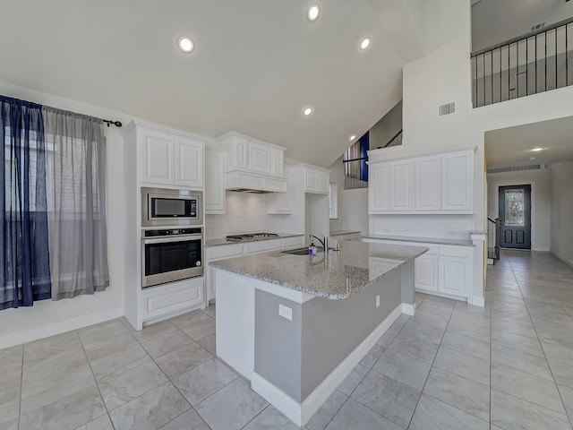 kitchen featuring light stone countertops, sink, stainless steel appliances, high vaulted ceiling, and white cabinets