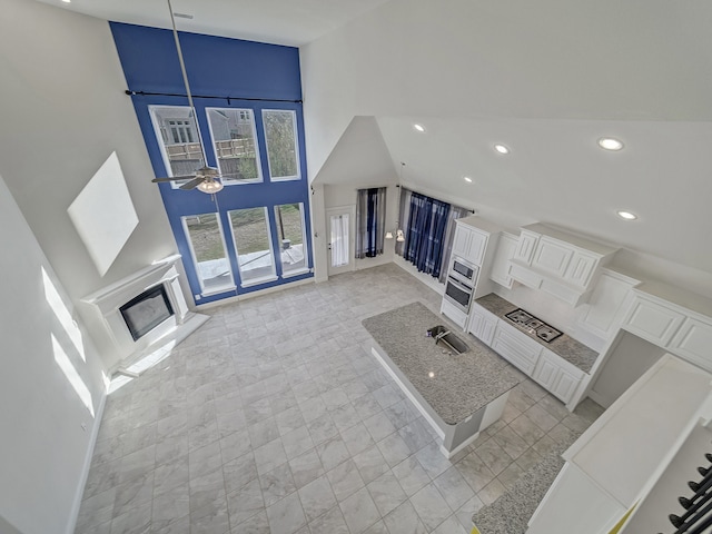 unfurnished living room featuring high vaulted ceiling, ceiling fan, and sink