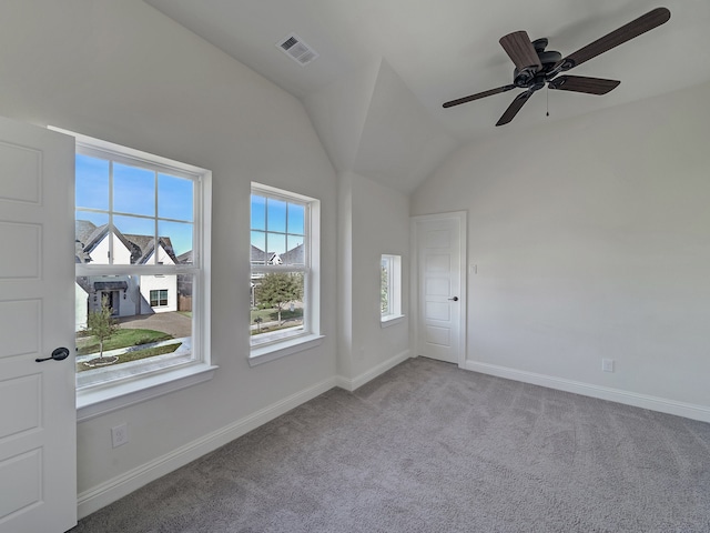 empty room featuring ceiling fan, plenty of natural light, light colored carpet, and vaulted ceiling