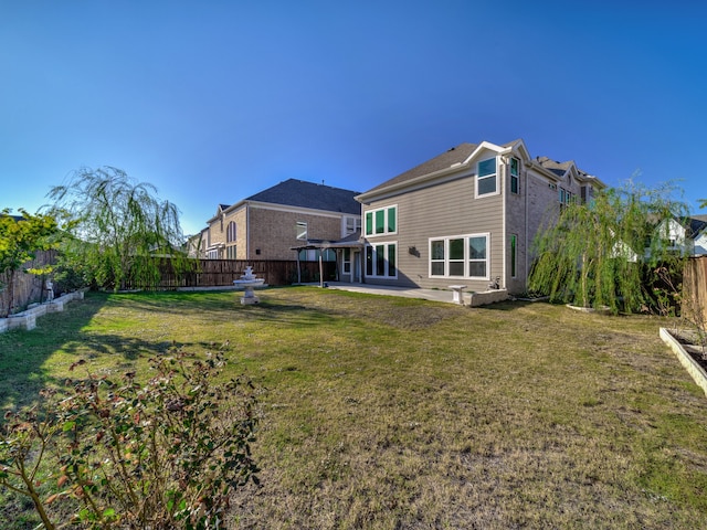 rear view of house featuring a lawn and a patio area