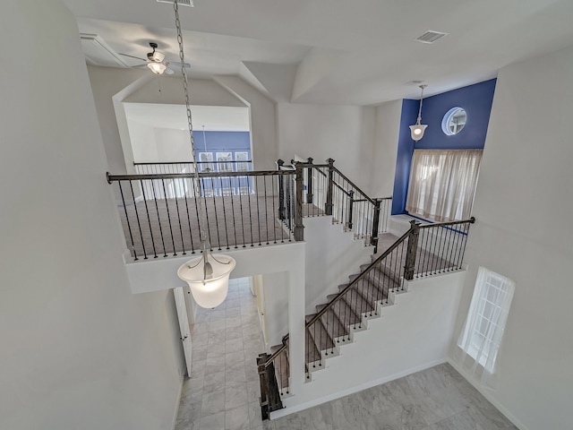 staircase with ceiling fan with notable chandelier and a towering ceiling