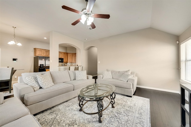 living room featuring lofted ceiling, dark wood-type flooring, and ceiling fan with notable chandelier