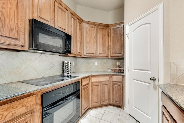 kitchen featuring decorative backsplash, light stone countertops, black appliances, and light tile patterned floors