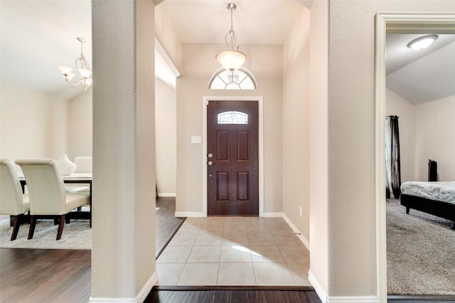 entryway featuring light hardwood / wood-style floors, vaulted ceiling, and a chandelier