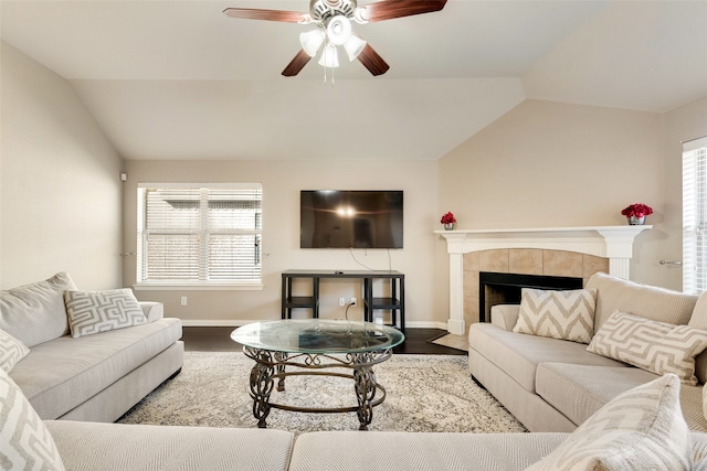 living room featuring lofted ceiling, hardwood / wood-style floors, a tiled fireplace, and ceiling fan