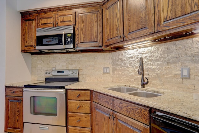 kitchen featuring sink, light stone countertops, stainless steel appliances, and tasteful backsplash