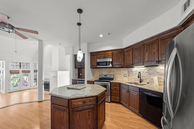 kitchen featuring pendant lighting, french doors, sink, appliances with stainless steel finishes, and a kitchen island