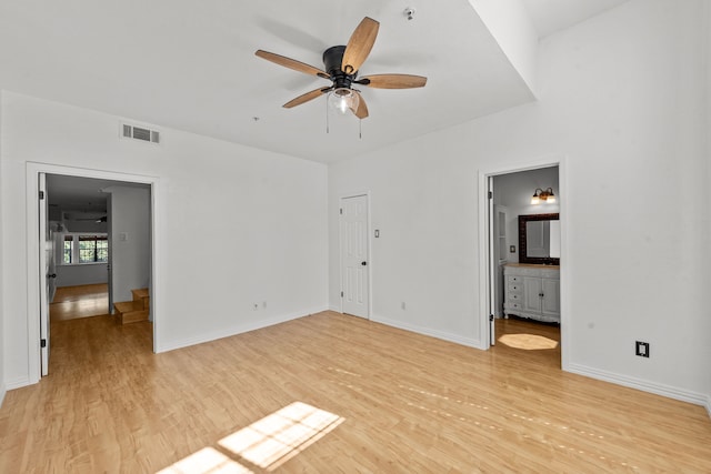 interior space with light wood-type flooring, ensuite bath, and ceiling fan