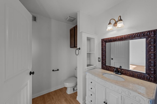 bathroom with hardwood / wood-style flooring, built in shelves, toilet, and vanity