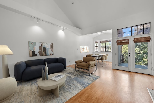 living room with ceiling fan, french doors, light hardwood / wood-style flooring, track lighting, and lofted ceiling