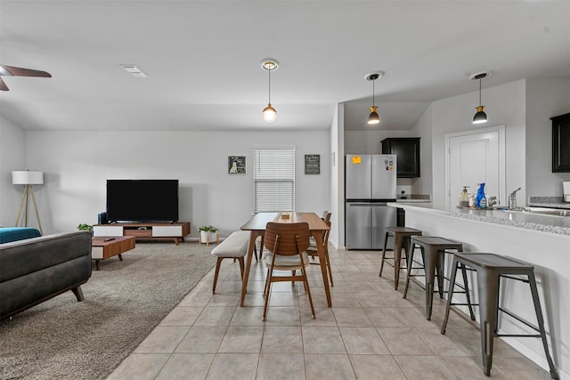 dining space with light carpet, ceiling fan, and sink