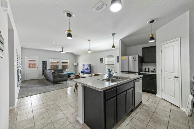 kitchen featuring ceiling fan, sink, stainless steel appliances, light colored carpet, and a center island with sink