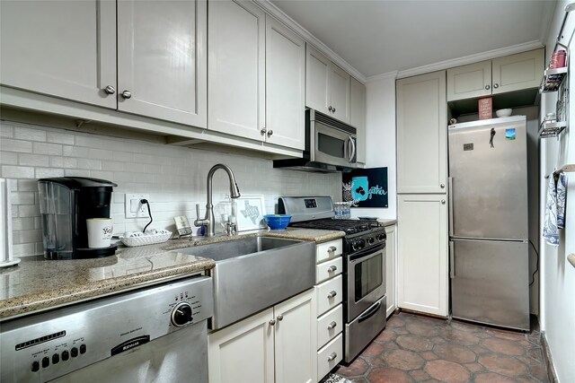 kitchen with a sink, light stone countertops, tasteful backsplash, and appliances with stainless steel finishes