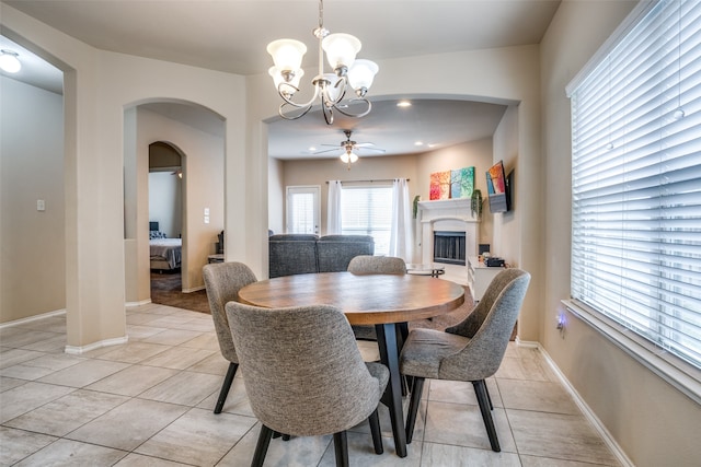 tiled dining area with ceiling fan with notable chandelier