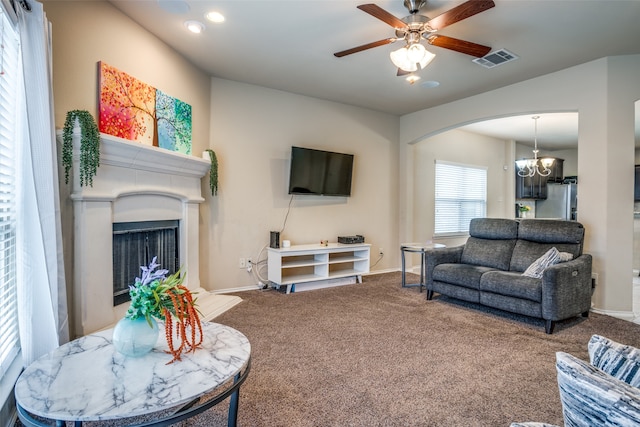 living room featuring carpet and ceiling fan with notable chandelier