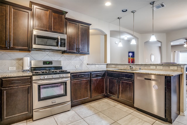 kitchen with appliances with stainless steel finishes, sink, ceiling fan, dark brown cabinetry, and pendant lighting