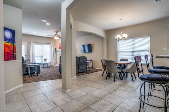 carpeted dining room featuring ceiling fan with notable chandelier