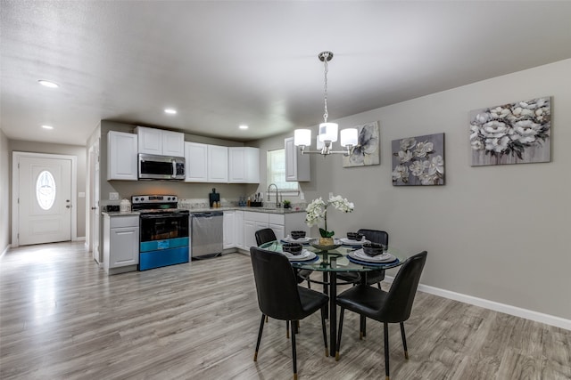 dining space with light hardwood / wood-style flooring, a chandelier, sink, and a wealth of natural light