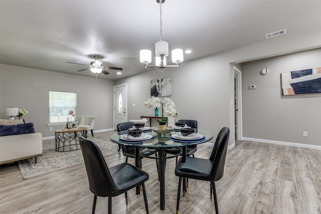 dining space featuring ceiling fan with notable chandelier and light wood-type flooring