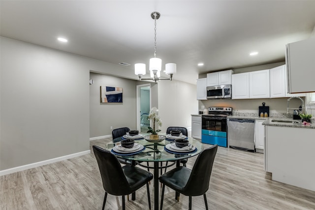 dining room featuring light hardwood / wood-style floors, sink, and an inviting chandelier