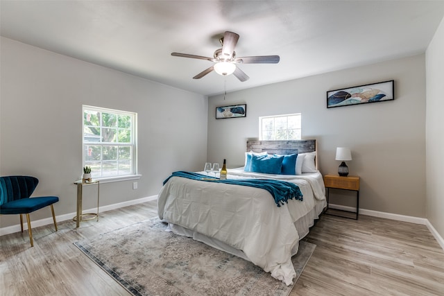 bedroom featuring multiple windows, light hardwood / wood-style floors, and ceiling fan