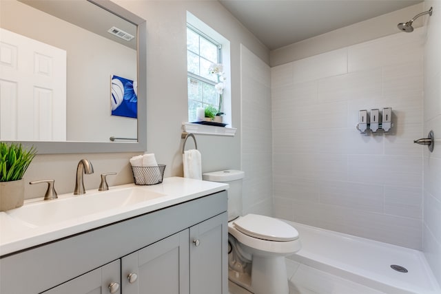 bathroom featuring vanity, toilet, and a tile shower