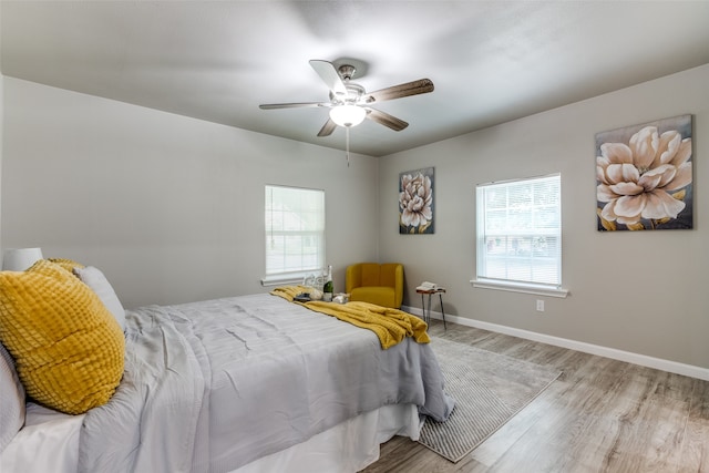 bedroom featuring ceiling fan, multiple windows, and light wood-type flooring