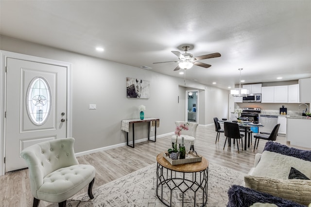 living room with sink, ceiling fan, and light hardwood / wood-style flooring