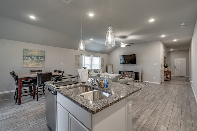 kitchen with an island with sink, white cabinetry, stainless steel dishwasher, light hardwood / wood-style floors, and sink