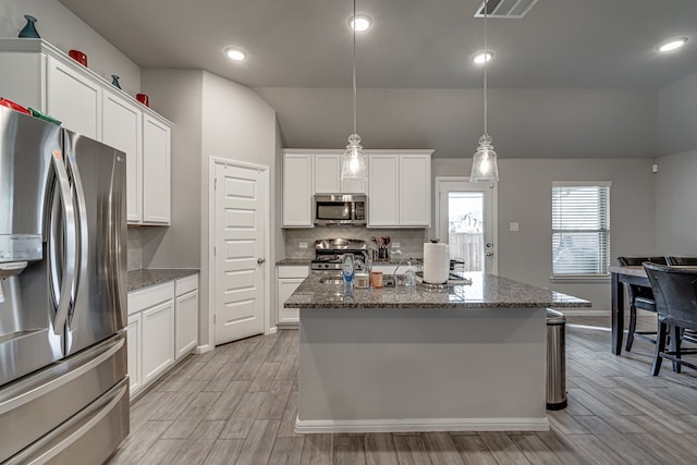 kitchen with appliances with stainless steel finishes, decorative light fixtures, and white cabinetry