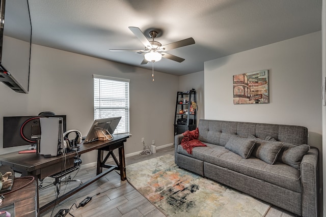 home office with a textured ceiling, light wood-type flooring, and ceiling fan