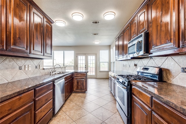 kitchen featuring light tile patterned floors, stainless steel appliances, sink, and backsplash