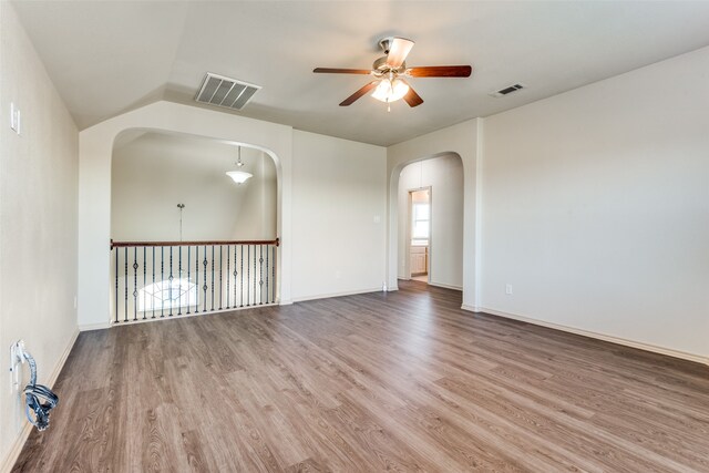 empty room with ceiling fan, vaulted ceiling, and hardwood / wood-style floors